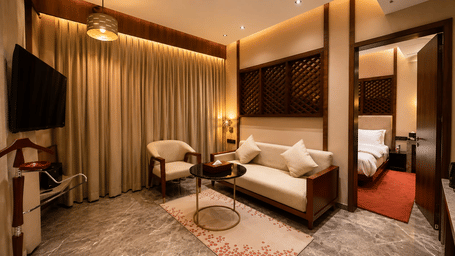 Spacious living area in the Zari suite at Ni Central Park showing sofa seating, coffee table, and bedroom doorway.