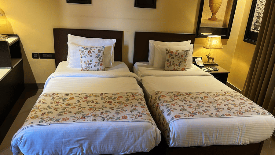 Two neatly made twin beds with matching patterned bedding at Aamaghati Wildlife Resort.