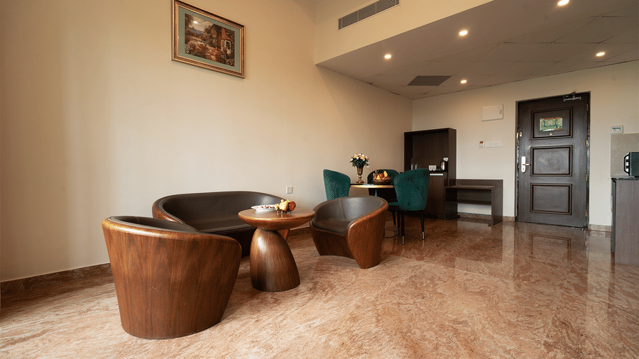 A wide angle shot of a living area with cosy chairs and a teapoy in Studio Two Bedroom Suite at Accord Chrome Airport Hotel