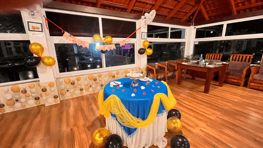 An indoor dining area decorated for a party with a covered table and balloons at Coorg Orange Blossom Resort & Spa