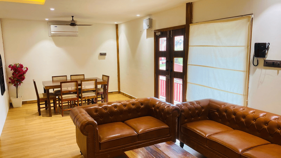 Spacious living area within a suite featuring leather sofas and a dining table - DAN Resorts & Weddings, Palghar