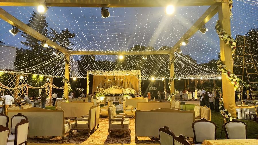 An outdoor wedding venue with a wooden stage, string lights, and seating arrangements for guests.