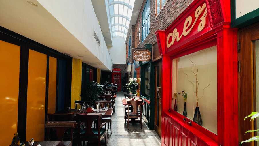 Indoor street-style cafe at Fragrant Nature Cochin, featuring an alleyway setting with neatly arranged tables and chairs.