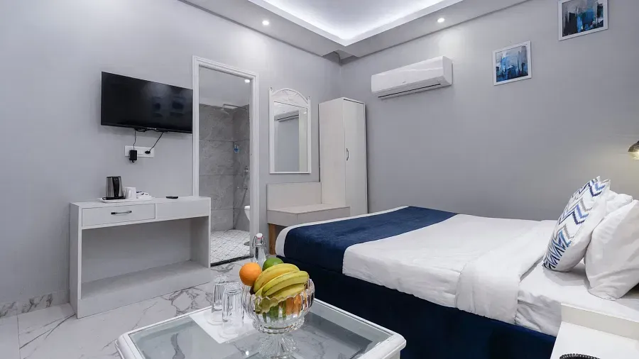 Super Deluxe Room featuring a king size bed with white linens and a blue accent, a fruit basket, and a bedside table. - Hotel Downtown17, Chandigarh