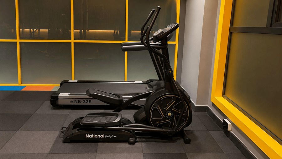 A fitness area at Hotel Sonar Bangla, Mayapur, featuring an elliptical trainer, a treadmill, and floor mats.