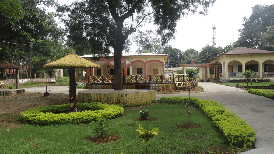 A view across a lawn area at Khairi Resorts shows green grass and a covered outdoor seating shelter in the centre.
