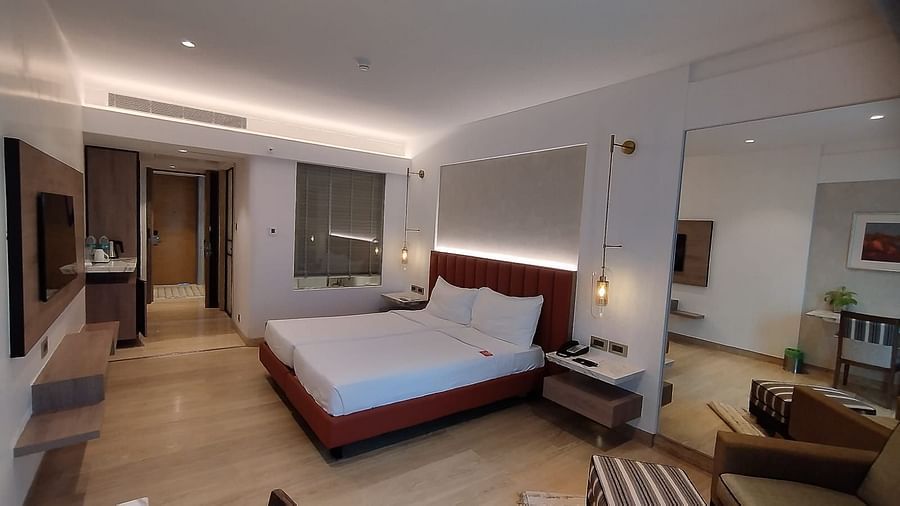 A well furnished executive bedroom in Mirage Hotel, featuring twin beds, a large mirror, and a wooden panelled entertainment unit.