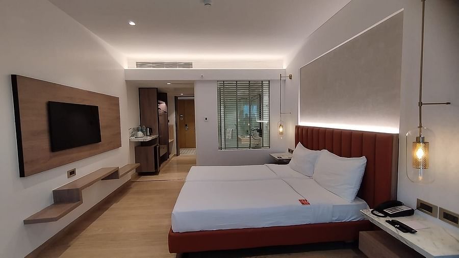A well-lit, wooden floored, executive room in Mirage Hotel, featuring twin beds with decorative head-rest and a wooden panelled entertainment unit.