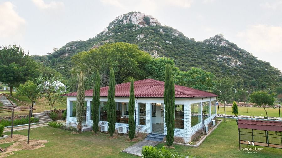 Facade of a building with tress around it and mountains in the background at Valley by Grassfield.