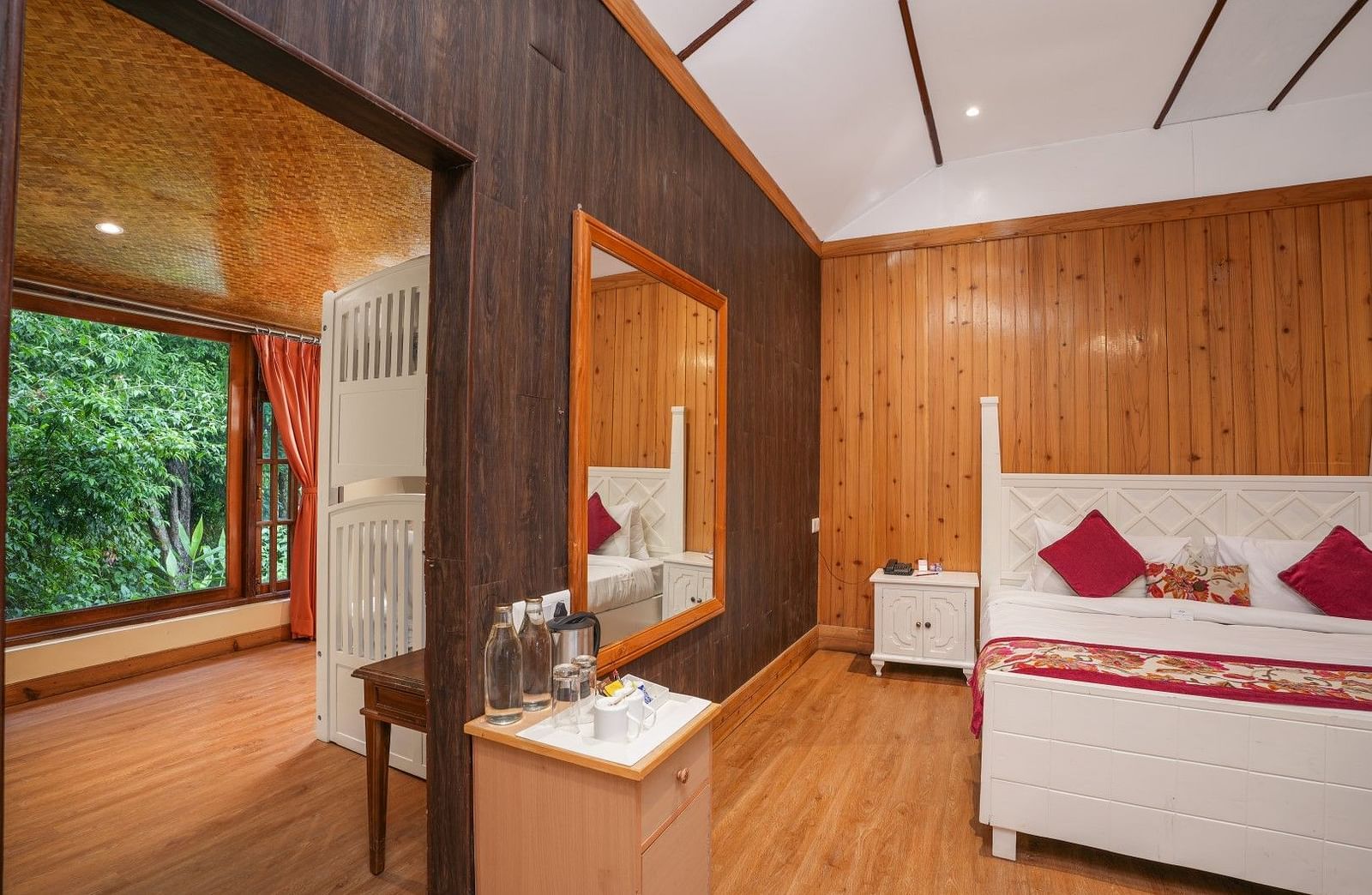 A room at Summit Barsana Resort & Spa, Kalimpong wih a double bed, a large window and wooden panelling
