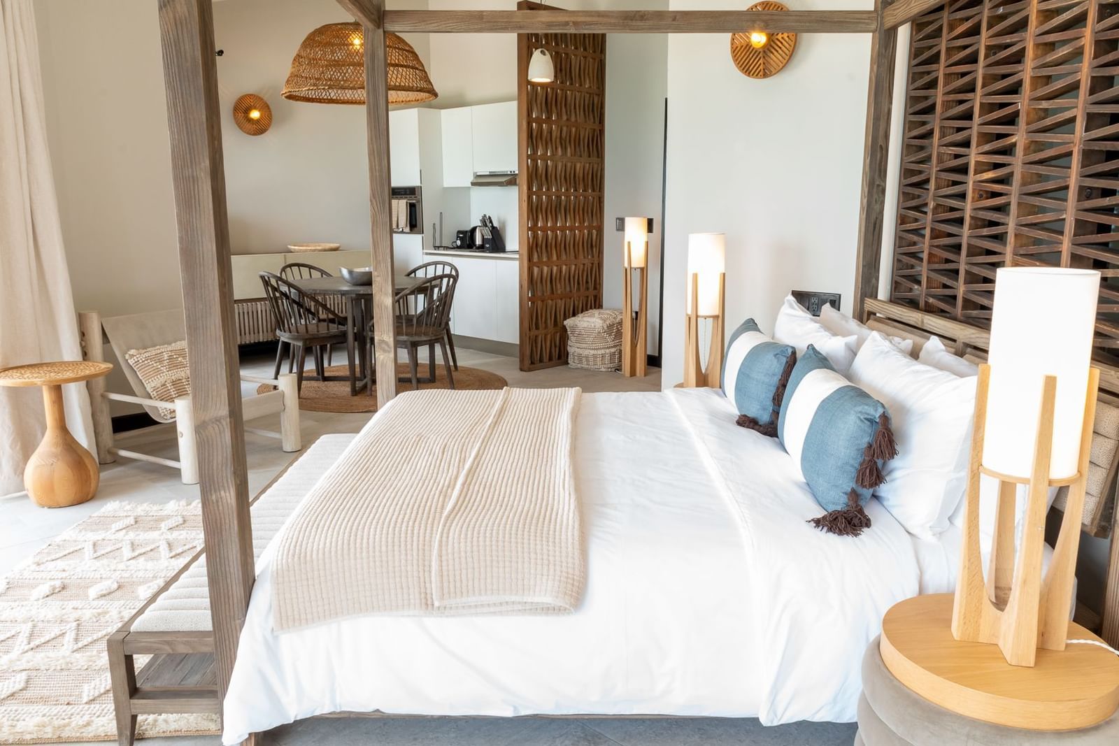 A studio room with a plush bed, natural wood accents, and a seamless flow into a dining area at the Tamarind Hills Resort and Villas, Antigua.