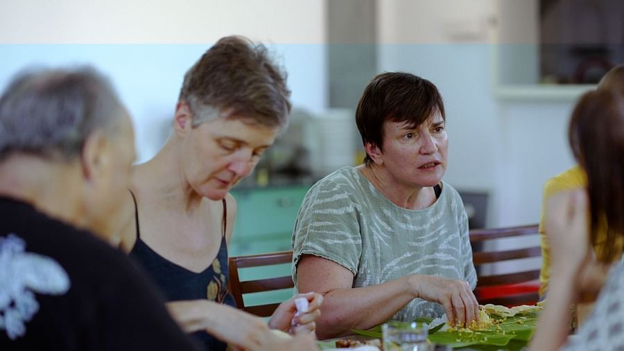 A group of people are seated around a table indoors, sharing a meal and conversation.