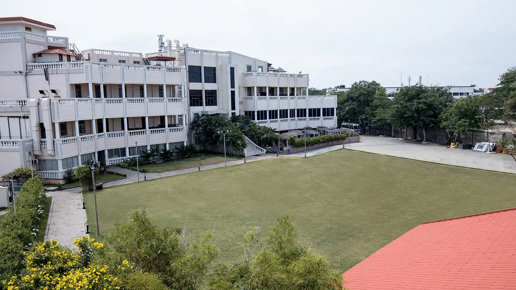  A multi-story white building with a large green lawn in front.