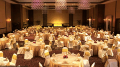 A conference hall in Mumbai with round linen-covered tables set for a formal event at The Retreat Hotel and Convention Centre.