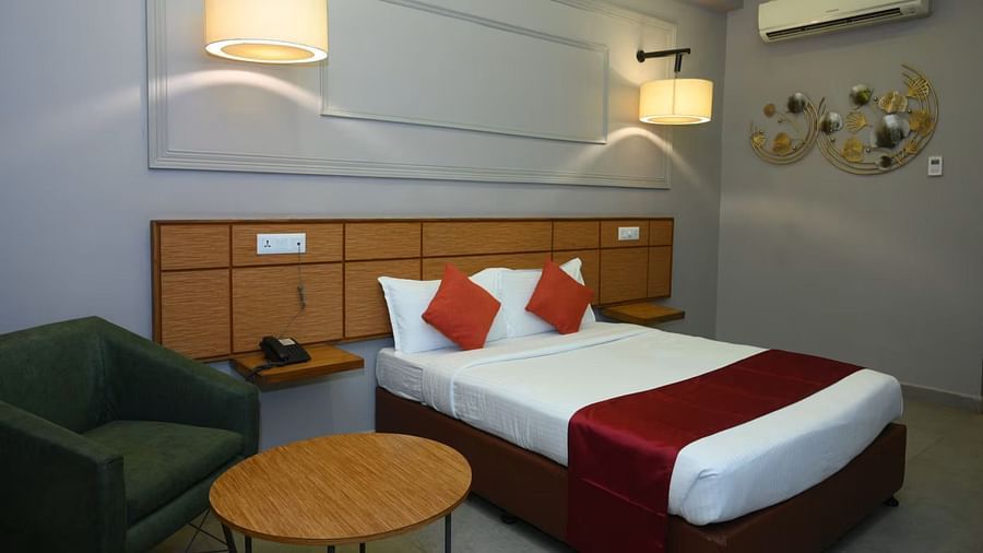 An overview of a room with a double bed and a black single seater sofa inside one of the rooms - Max Hotel Prayagraj