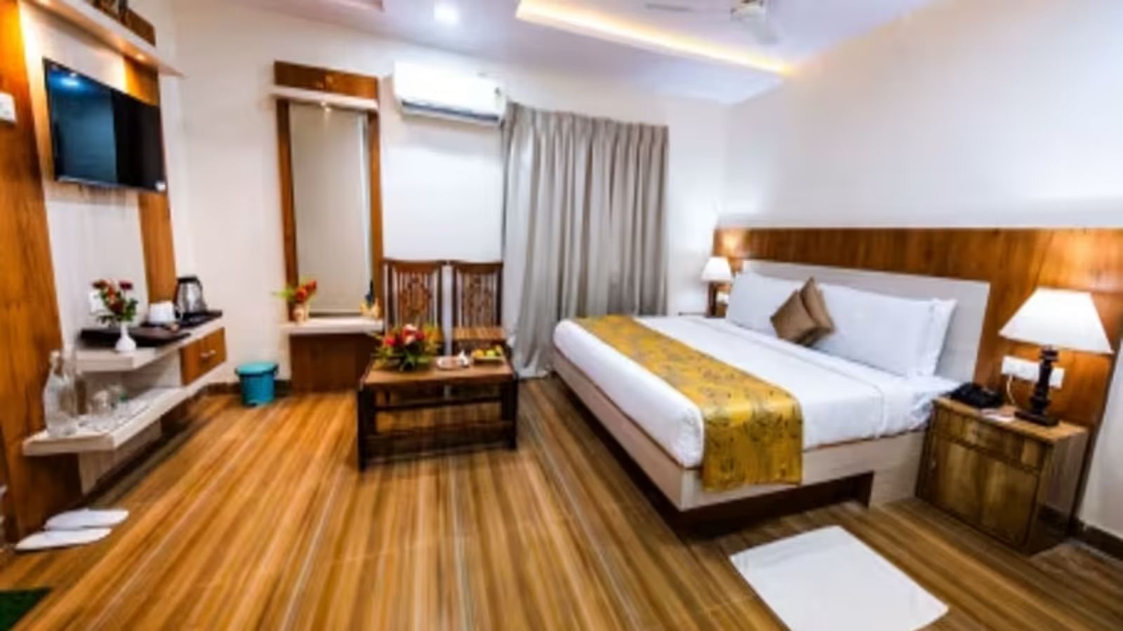  A spacious room with a large bed, wooden bedside tables on either side, and a wall-mounted television facing the bed.