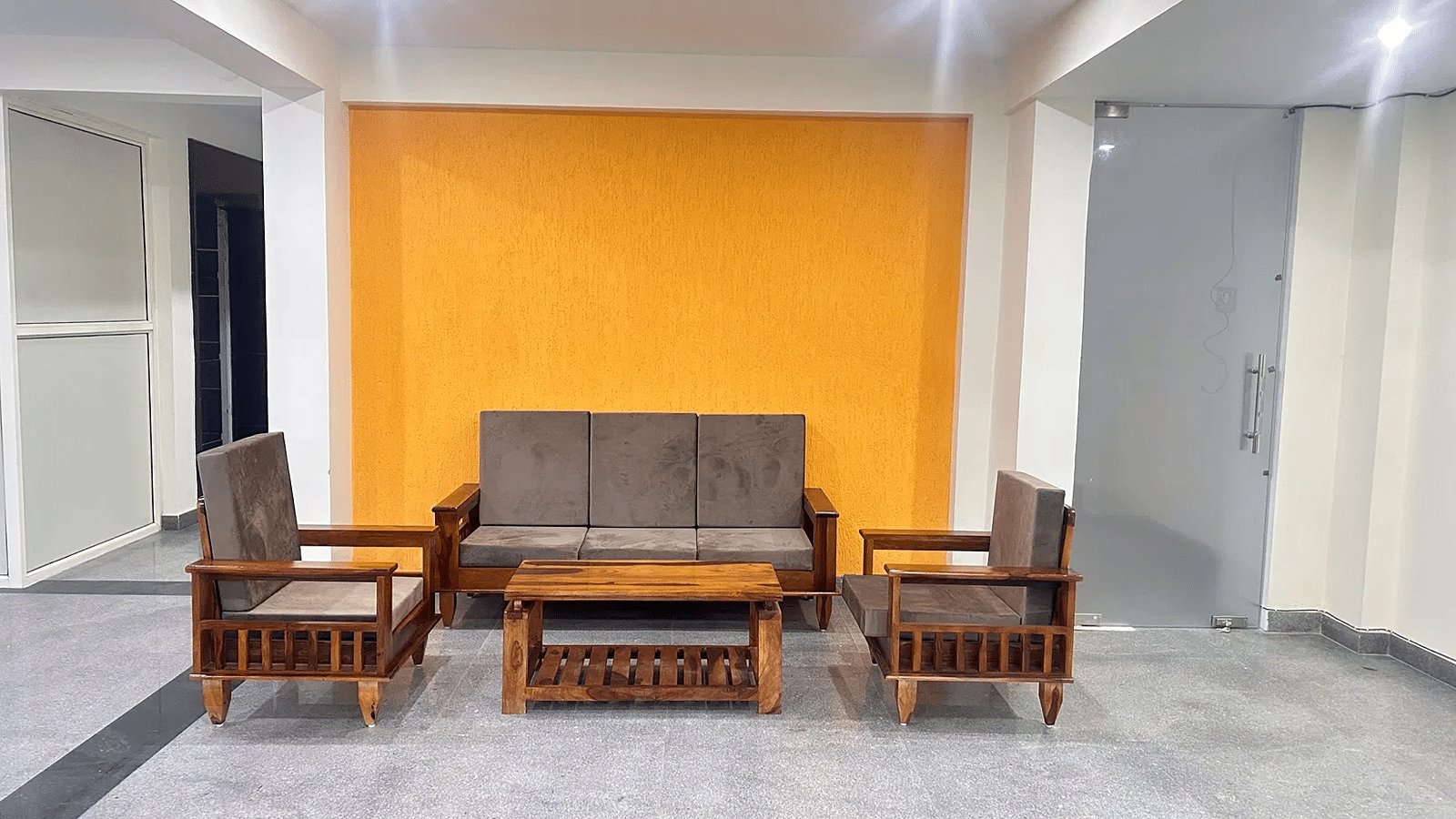 Spacious living room with sofa seating wooden centre table and accent wall at Lime Tree 1BHK Serviced Apartment Near Medanta Hospital Gurgaon ideal for relaxation