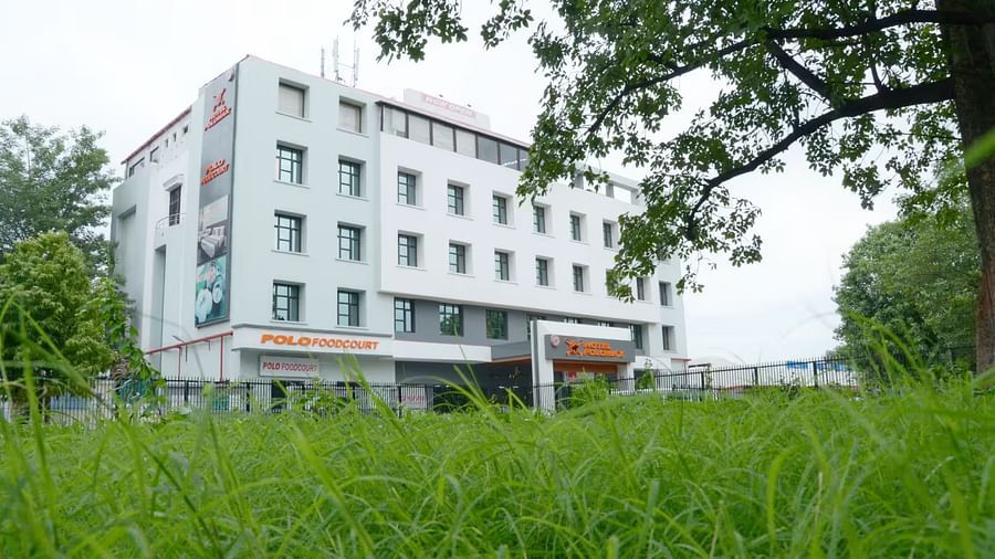 Facade view of Max Hotel Prayagraj with lush green garden in the front and clear sky in the background.