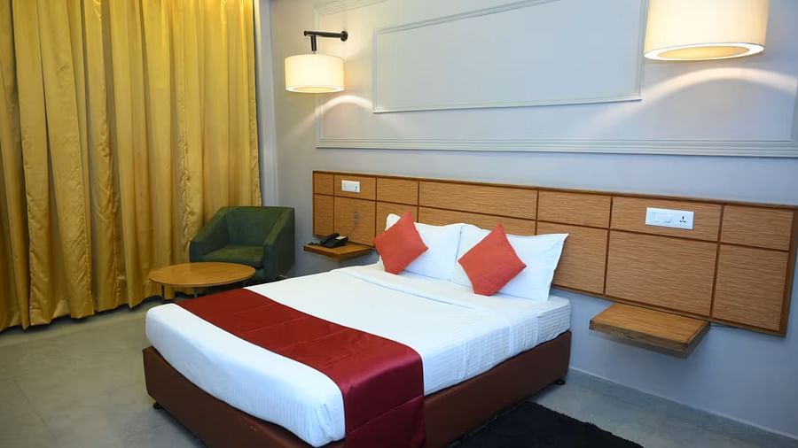View of a spacious hotel room with a comfortable bed, modern furnishings, and ambient lighting - Max Hotel Prayagraj.