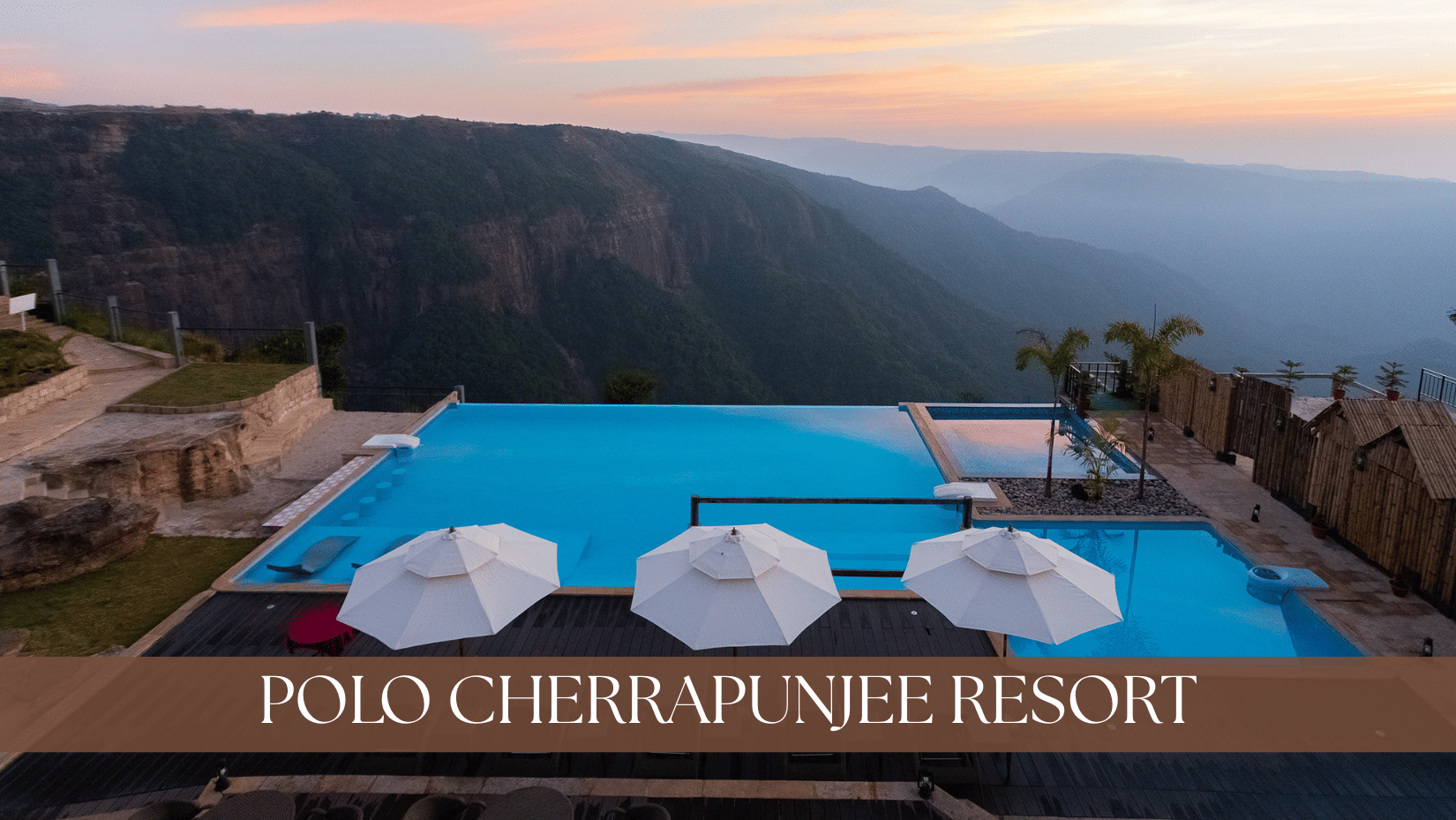 The infinity pool at Polo Resort Cherrapunji, with a pool, and umbrellas placed in the seating area.