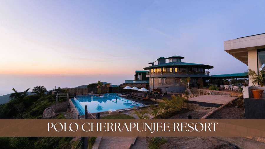 The outdoor at Polo Cherrapunjee Resort, featuring an infinity pool, umbrellas placed in the seating area, and the facade.