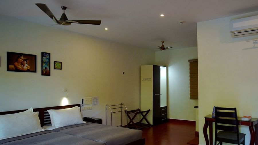 A simply furnished hotel room with a bed, desk, and ceiling fan.