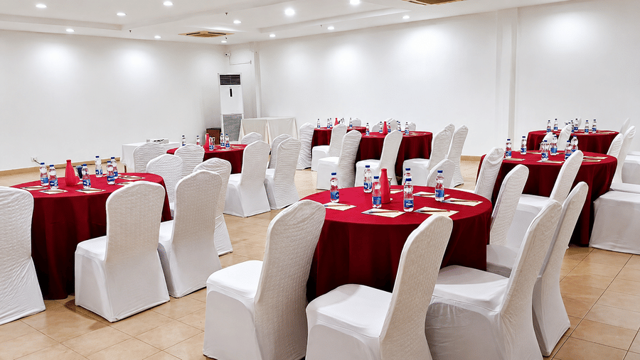 Marigold Hall set up with round tables in red linens and white chair covers at Chariot Beach Resort, ideal for elegant events.