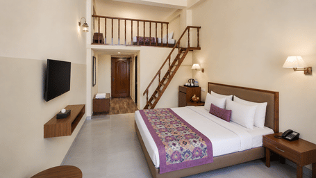 Family Suite at Valmere Himalayan Hotel & Spa, Gangtok with a king-size bed, wall-mounted TV, a wooden staircase, and a loft bed visible above the hallway.