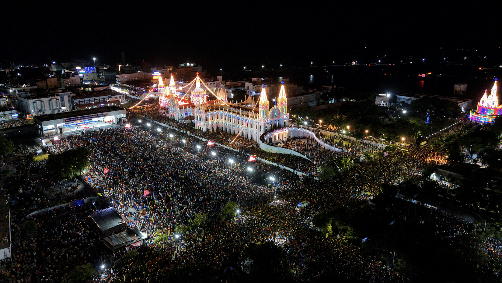 Aerial night view of the Vailankanni Flag Hoisting Festival 2026, with thousands of devotees gathered at the Basilica of Our Lady of Good Health to celebrate faith, tradition, and togetherness.