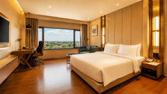 A room includes a king size bed, a wooden desk with an office chair, and a wall mounted television at Pride Plaza Indore.