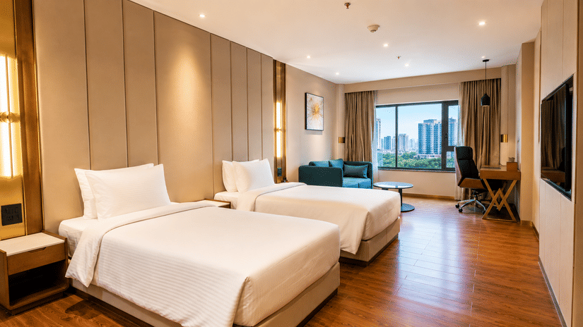 Superior Twin Room at Pride Plaza Indore featuring 2 single beds, a nightstand, a wall-mounted television, and a window with a city view.