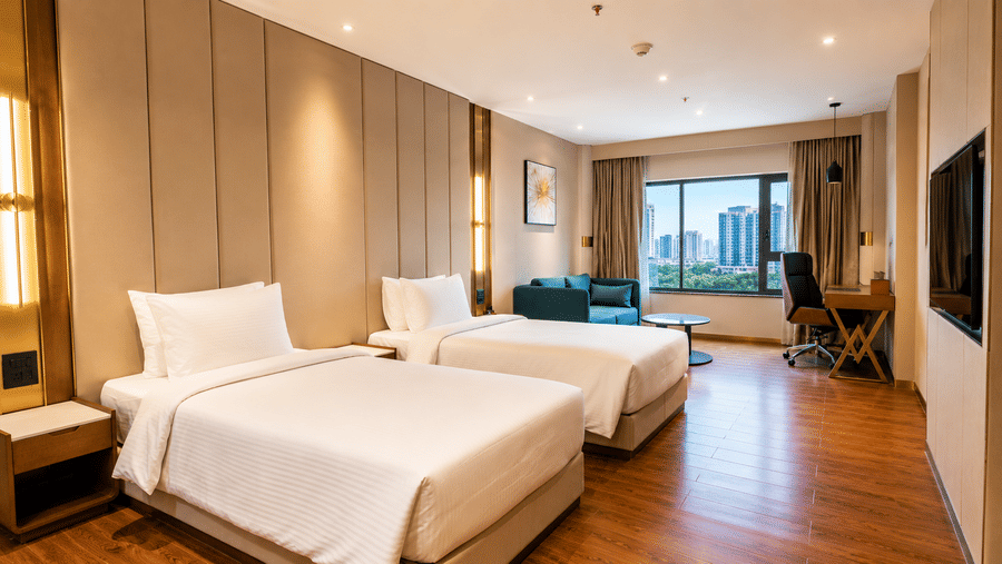 Superior Twin Room at Pride Plaza Indore featuring 2 single beds, a nightstand, a wall-mounted television, and a window with a city view.