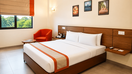 Max Queen Room at Max Hotel Jabalpur featuring a queen size bed, bedside tables and large windows with natural light.