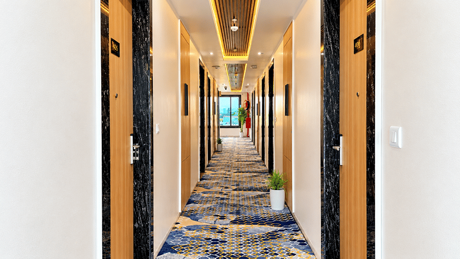 Carpeted corridor with doors on both sides at Daksh The Royal Braj, Vrindavan.