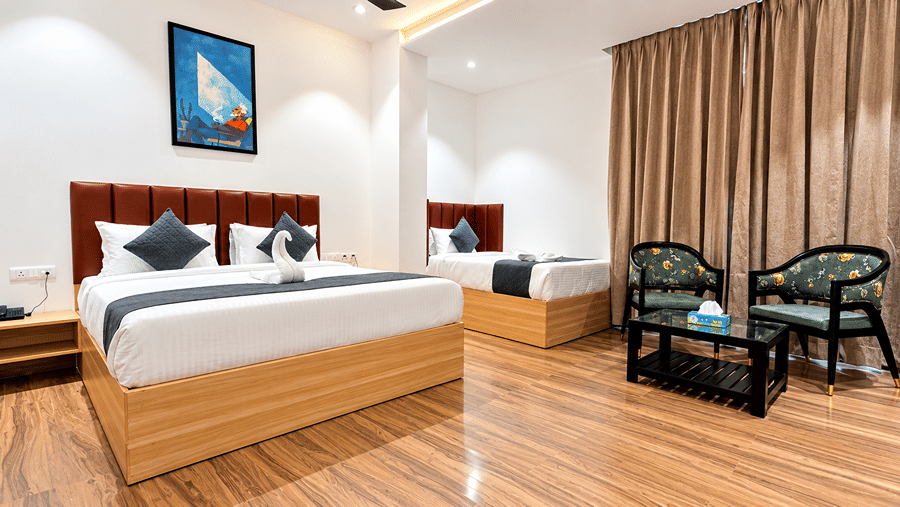 Room at Daksh The Royal Braj, Vrindavan, with a bed, two armchairs, a coffee table, curtains, and wooden flooring.