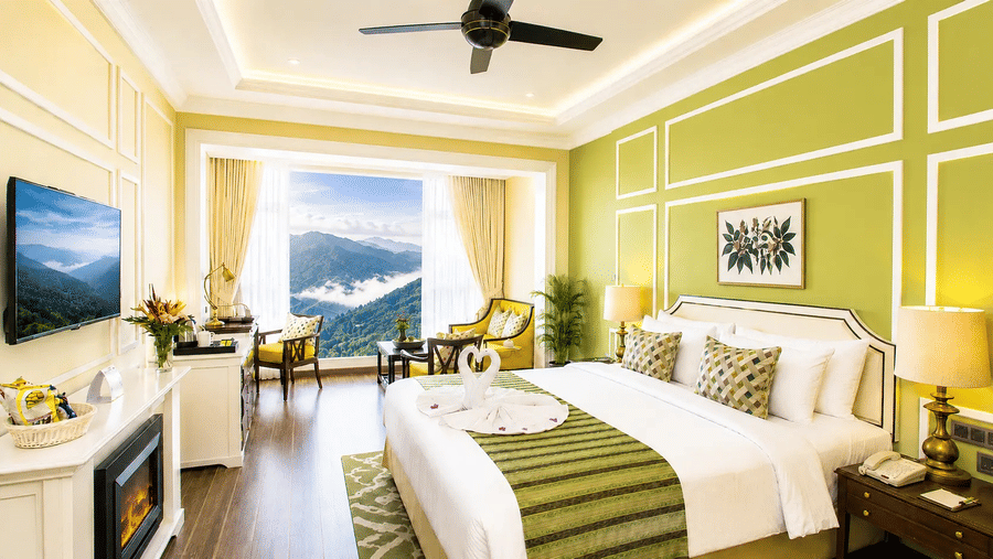 Tropic Green Room at Fragrant Nature Munnar with king bed, green accent wall, fireplace, and panoramic mountain view