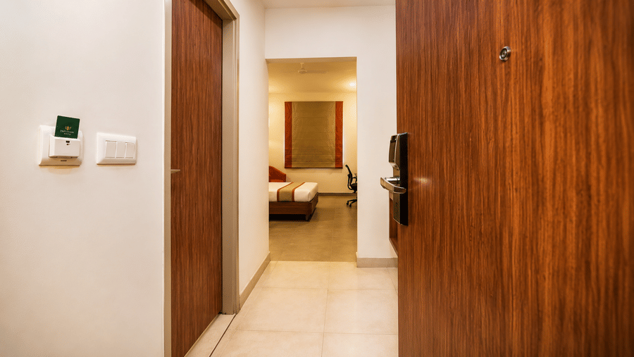 Entrance view of the Max Queen Room at Max Hotel Jabalpur showcasing the wooden door, wardrobe and bedroom.