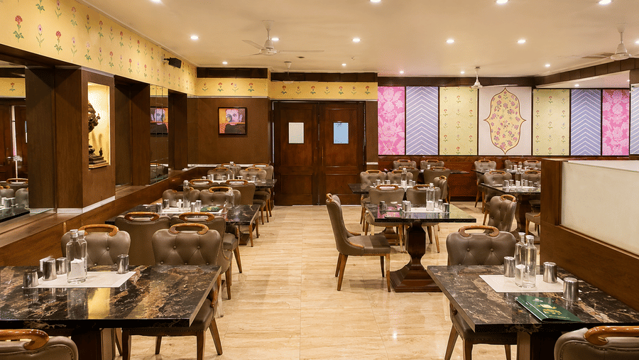 Super Snax restaurant with granite-topped tables, upholstered chairs, floral wall motifs, patterned panels and a tiled floor at MAYFAIR Garden, Rourkela.