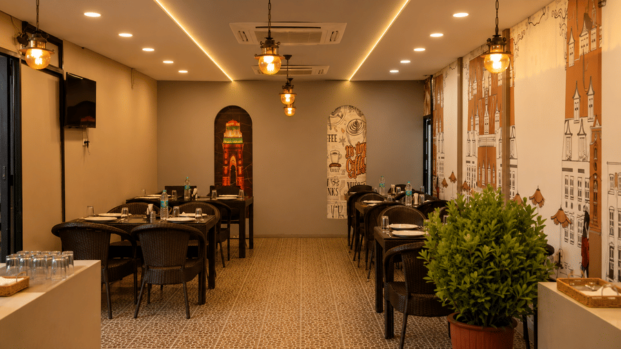 An illuminated dining space with tables and chairs at The Pamposh, New Delhi.