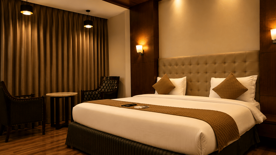 The Pamposh, New Delhi | A room with tables, a chair, a large bed, sporeads, pillows, and decorated wall.