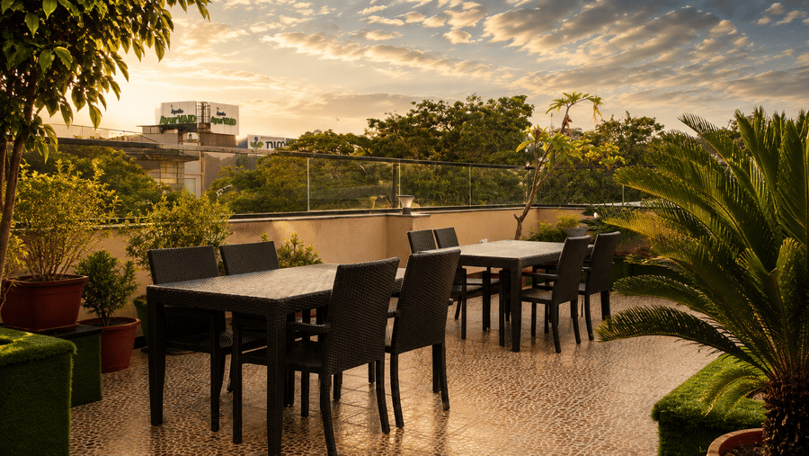 A rooftop resturant featuring chairs and tables set for dining with sky in the backdrop. | The Pamposh, New Delhi