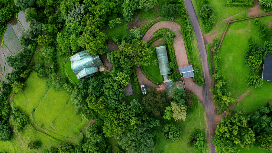 Aerial view of Wind Chalet, showing multiple chalet buildings, winding pathways, landscaped grounds, and dense forest surrounding the property.
