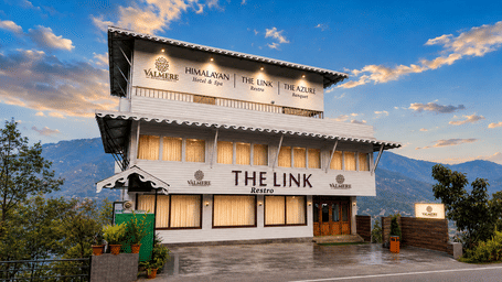 Exterior facade of Valmere Himalayan Hotel & Spa, Gangtok at dusk, showing The Link restro and The Azure banquet signage against a mountain backdrop.
