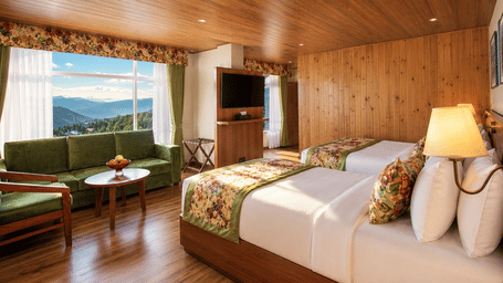 2 double beds, a sofa, a coffee table, a television, and a large window at Valmere Lungta Boutique Hotel & Spa, Darjeeling.