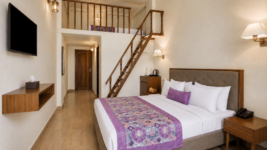 Family Suite at Valmere Himalayan Hotel & Spa, Gangtok, a duplex with a king-size bed, wall-mounted TV, and a wooden staircase to a mezzanine loft bed.