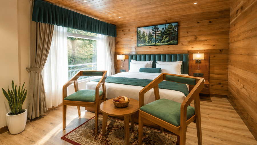 Bedroom with 2 wooden chairs, a king size bed, and coffee table at Valmere Lungta Boutique Hotel & Spa, Darjeeling.
