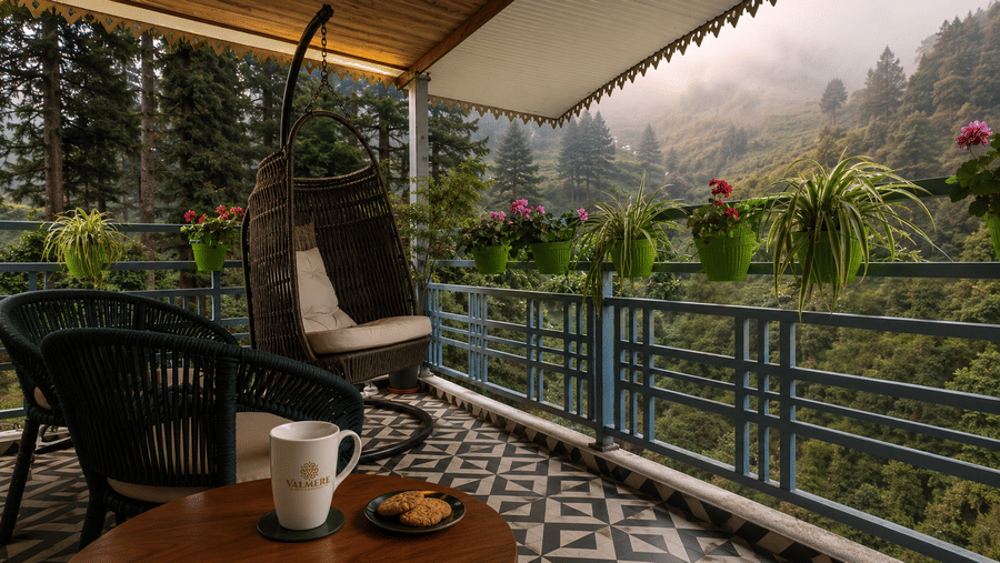 Balcony with 2 chairs, a hanging swing, and potted plants at Valmere Lungta Boutique Hotel & Spa, Darjeeling.