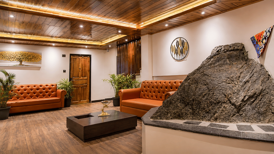 A indoor rock installation, 2 tufted leather sofas, a low coffee table, and a wall painting at Valmere Lungta Boutique Hotel & Spa, Darjeeling.