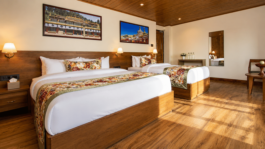 A king size bed, a double bed, framed wall artwork, bedside lamps, and a mirror at Valmere Lungta Boutique Hotel & Spa, Darjeeling.