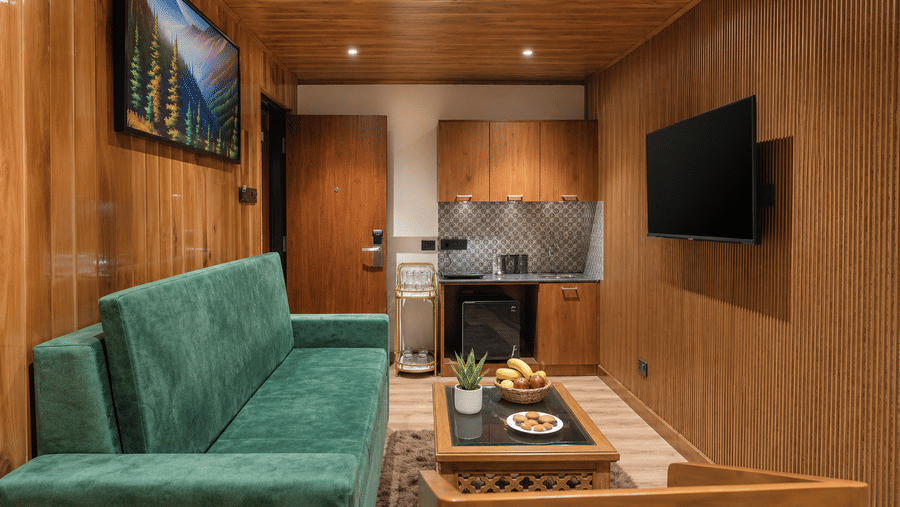 Lounge area with a sofa, wall television, and tea counter at Valmere Lungta Boutique Hotel & Spa, Darjeeling.